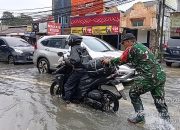 Anggota Babinsa Koramil Ciledug Bantu Warga Dorong Motor Melintasi Banjir